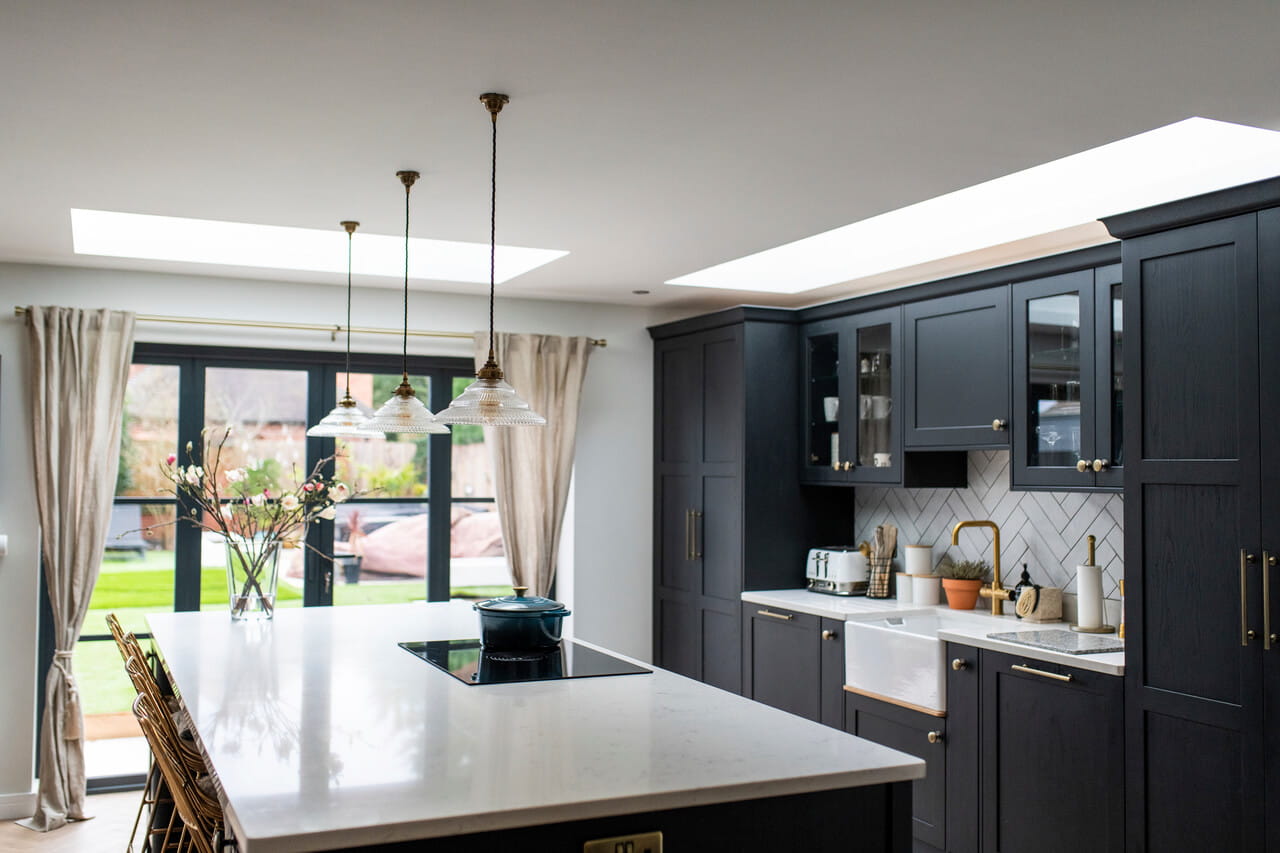 Bright kitchen area with dark painted cabinets and a flat roof window for more daylight.
