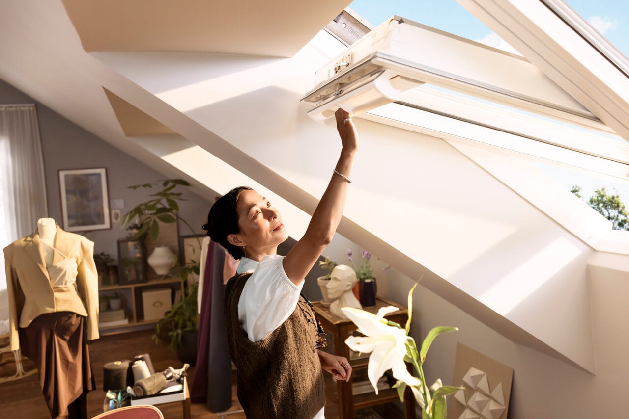Person opening VELUX roof window using a top handle