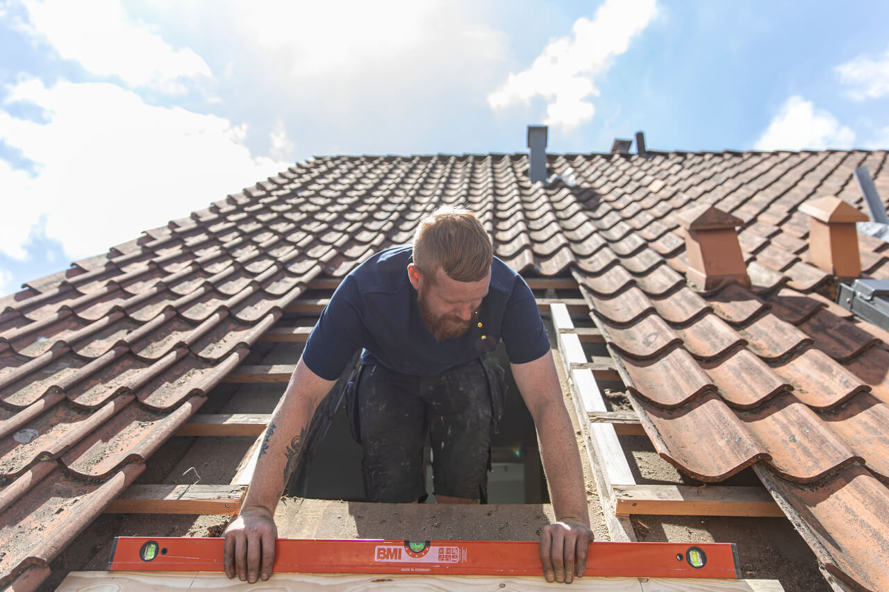 An installer making measurements on the roof.