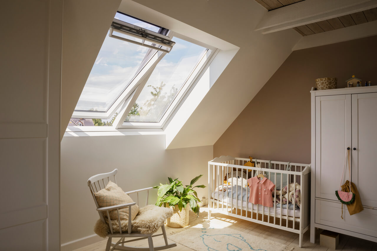 A bright kids room with a baby bed, chair and a closet and two room windows