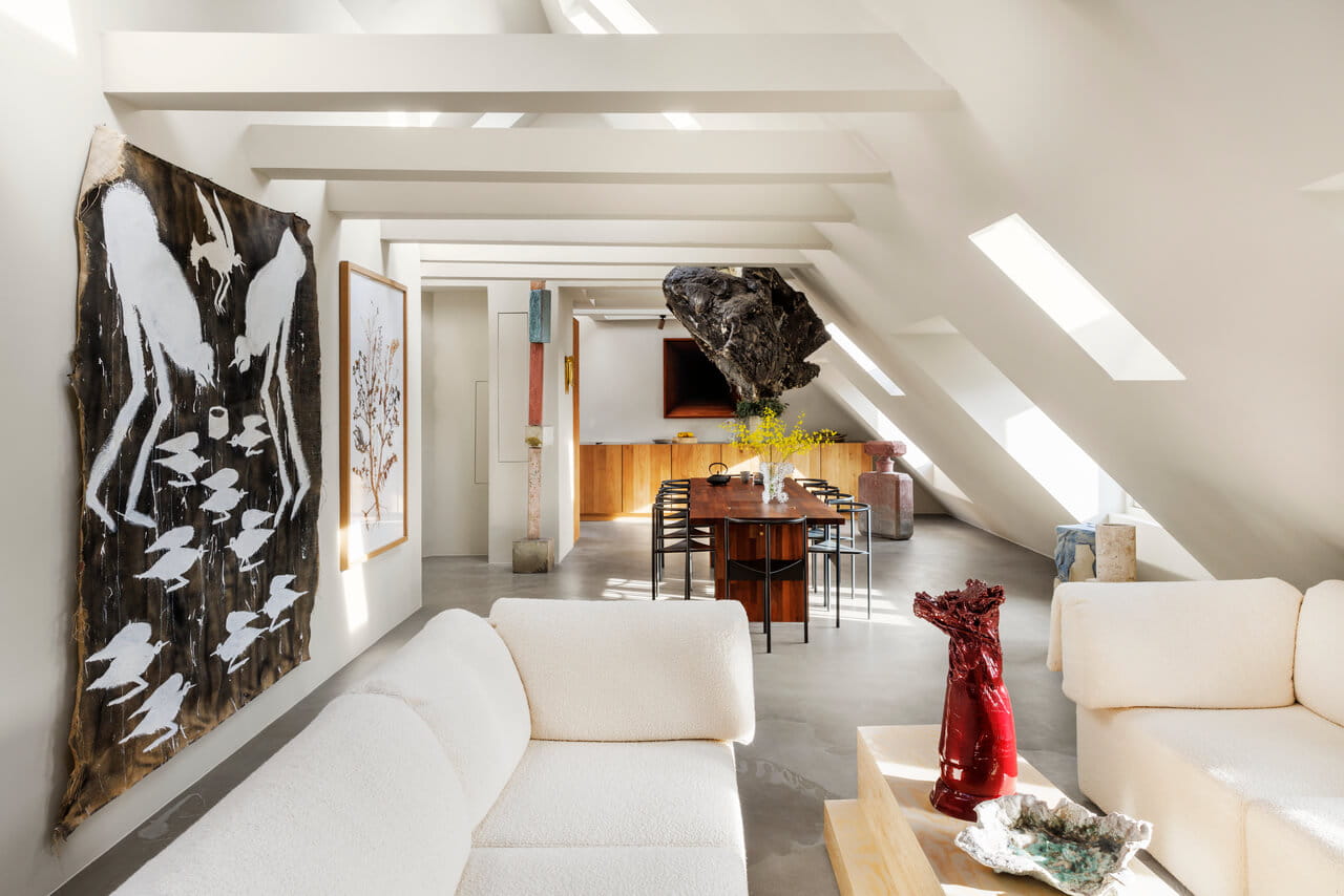 A bright living room space in the white painted attic with roof windows