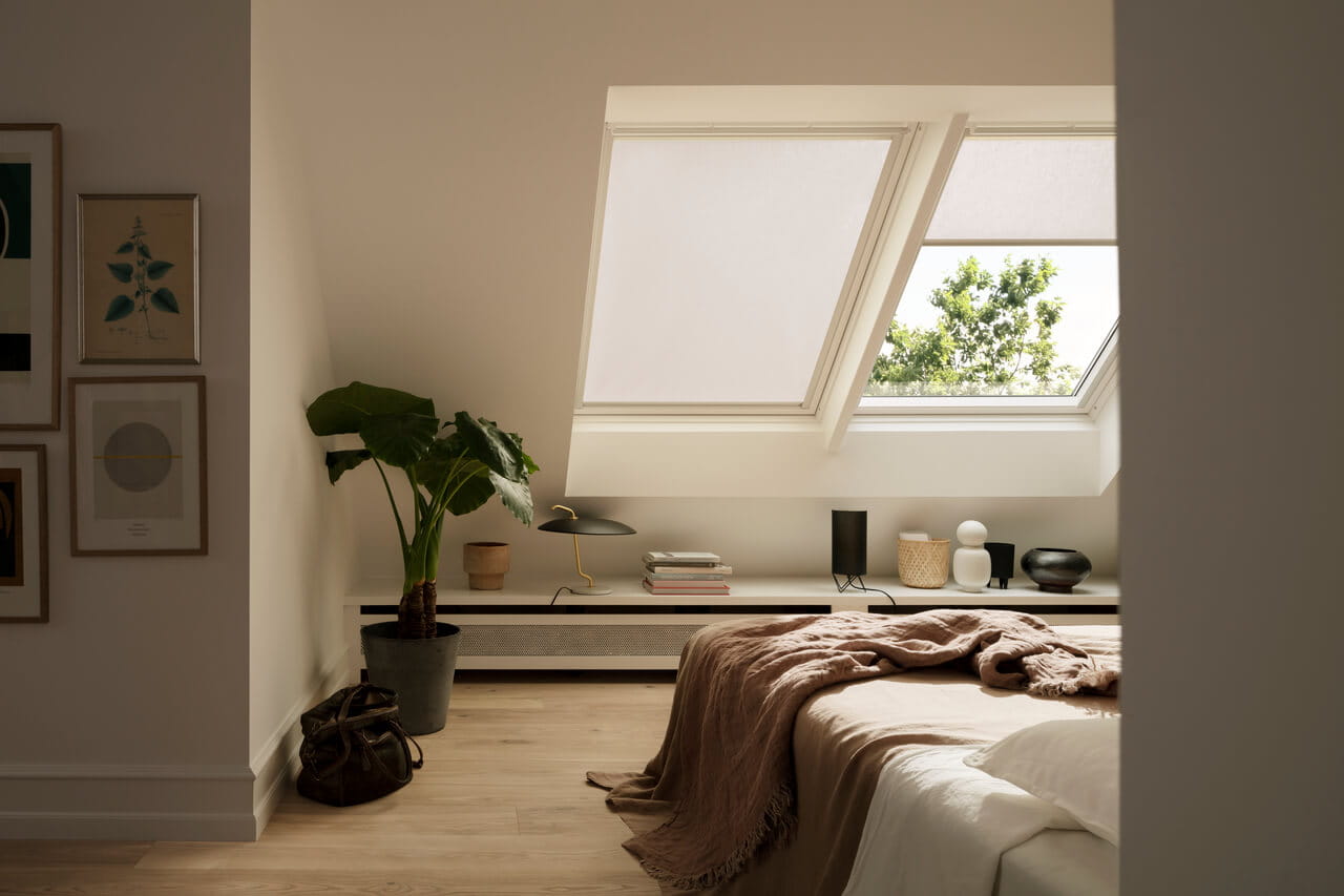 A bedroom with two roof windows with blinds