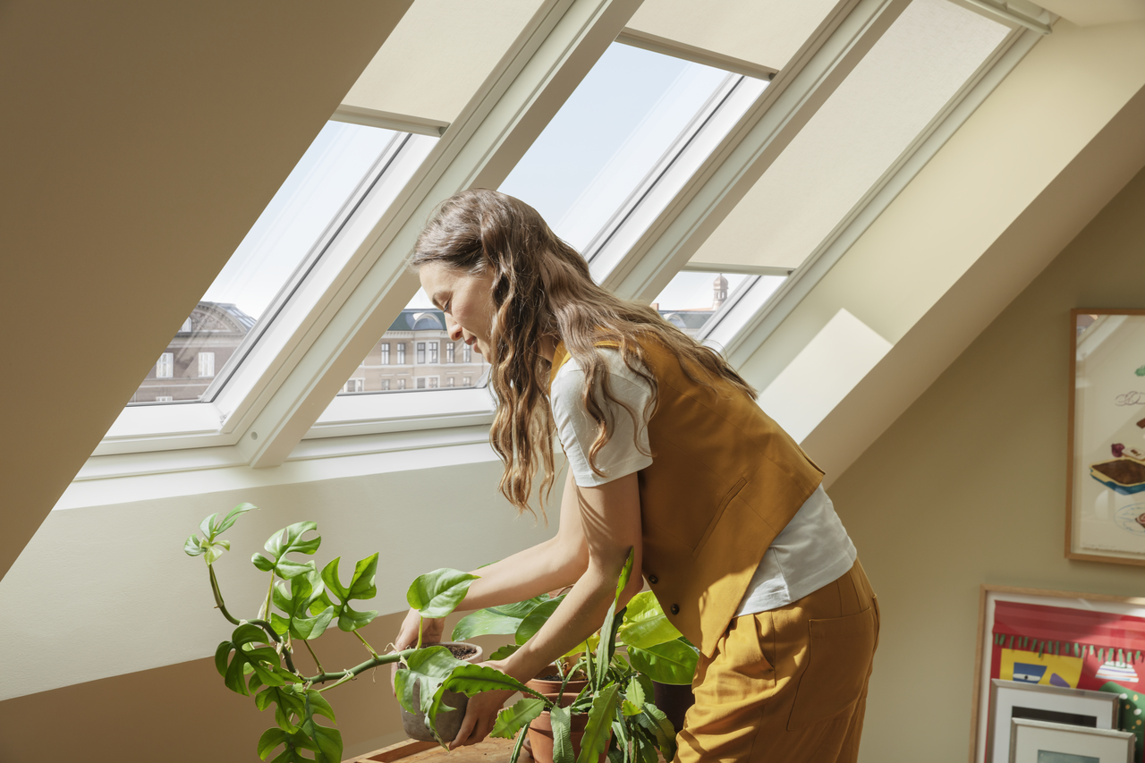 Woman watering plants by her VELUX 3in1 roof windows