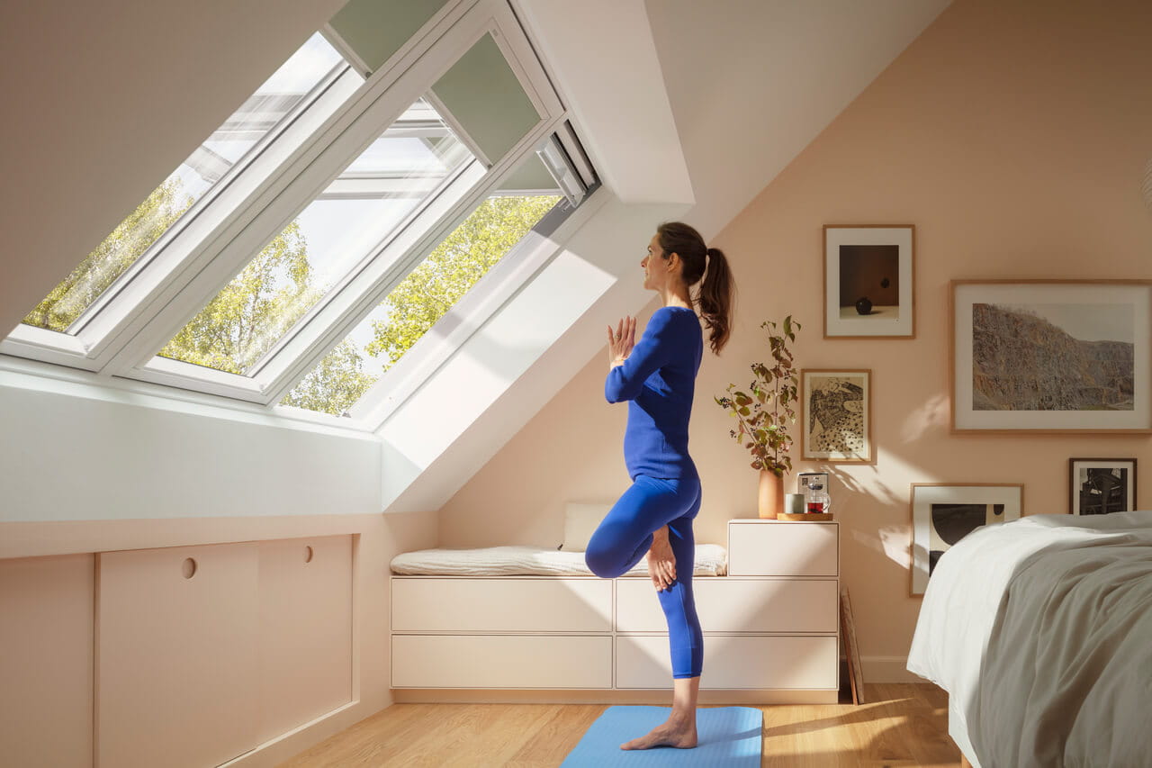 Woman in blue clothes doing yoga in front of roof window