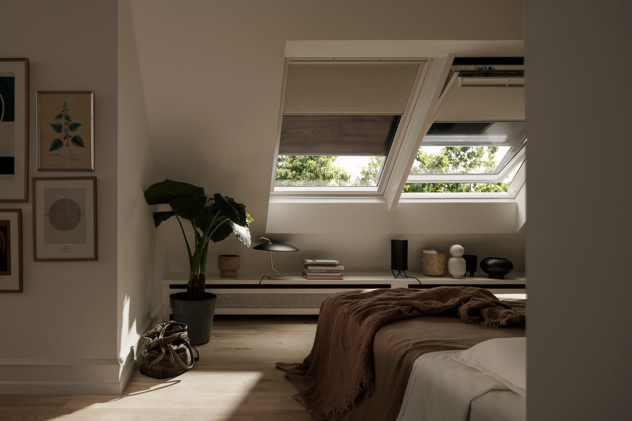 "A part of bedroom with bed and roof windows covered with blinds and shutters