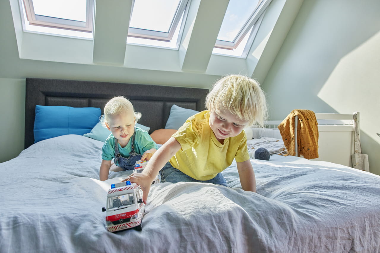 Two kids playing in bedroom with three VELUX roof windows