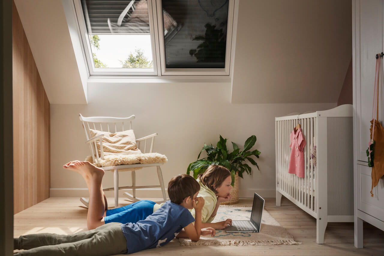 Two kids lying on the ground and watching laptop
