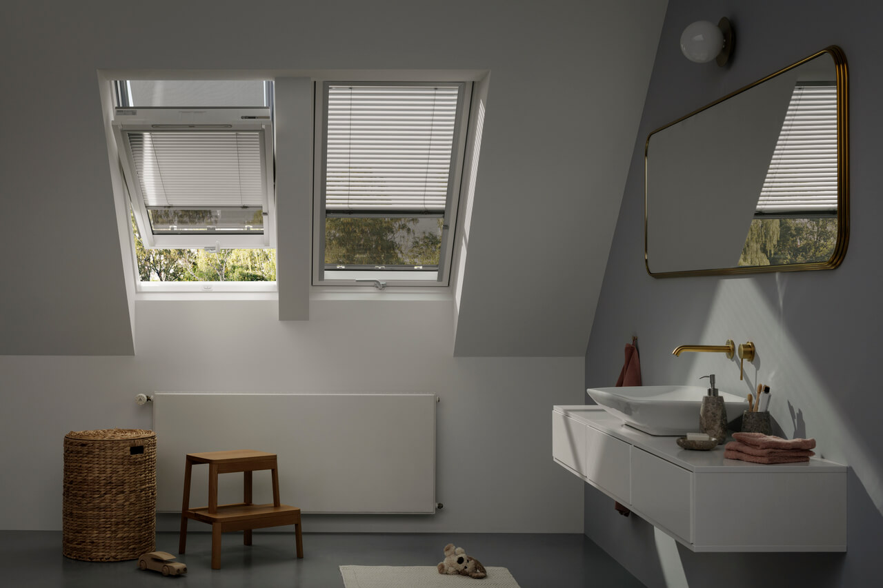A white painted bathroom area with sink and mirror and a two roof windows with blinds