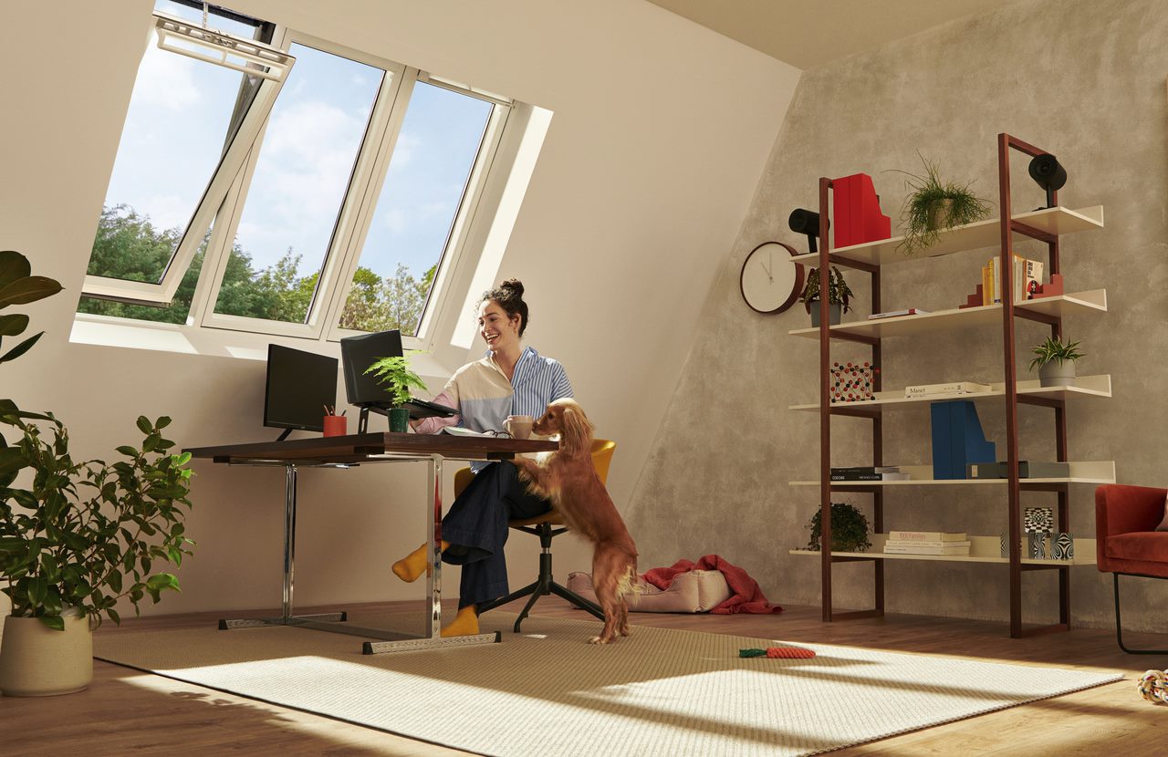 Woman sitting in her home office underneath VELUX 3-i-1 window