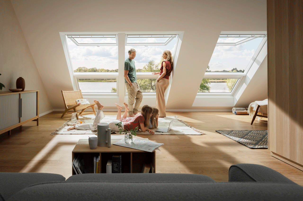 Man and woman sitting in their livingroom underneath VELUX 3-in-1 windows