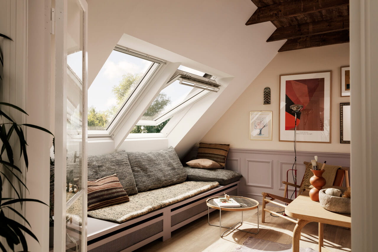 Living room in the attic with sofa, colourful paintings and an open roof window that allows for more fresh air to get into the room