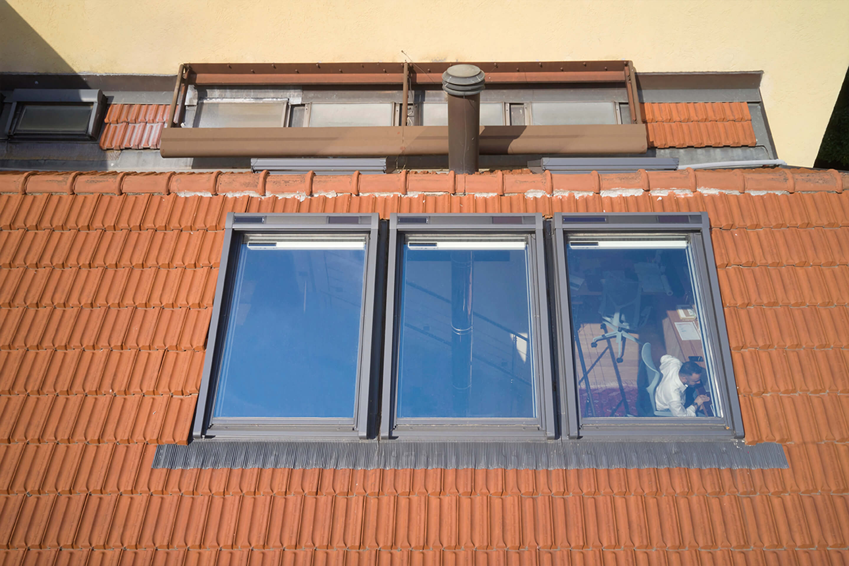 An outside view to a brown tiled roof with 3in1 roof windows