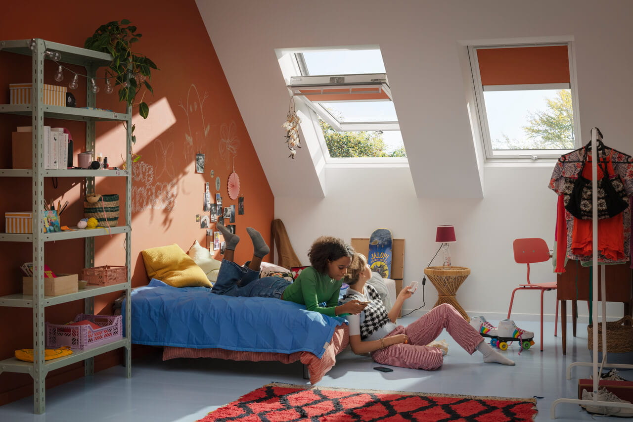 Two girls in a colourful kids room with two roof windows and blinds