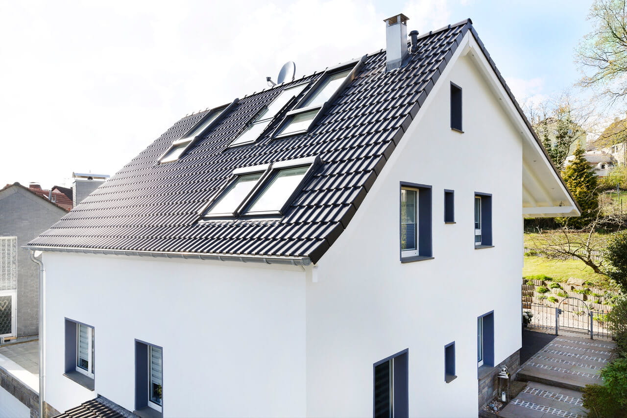 Outside view of a new built house painted in white with black roof and roof windows