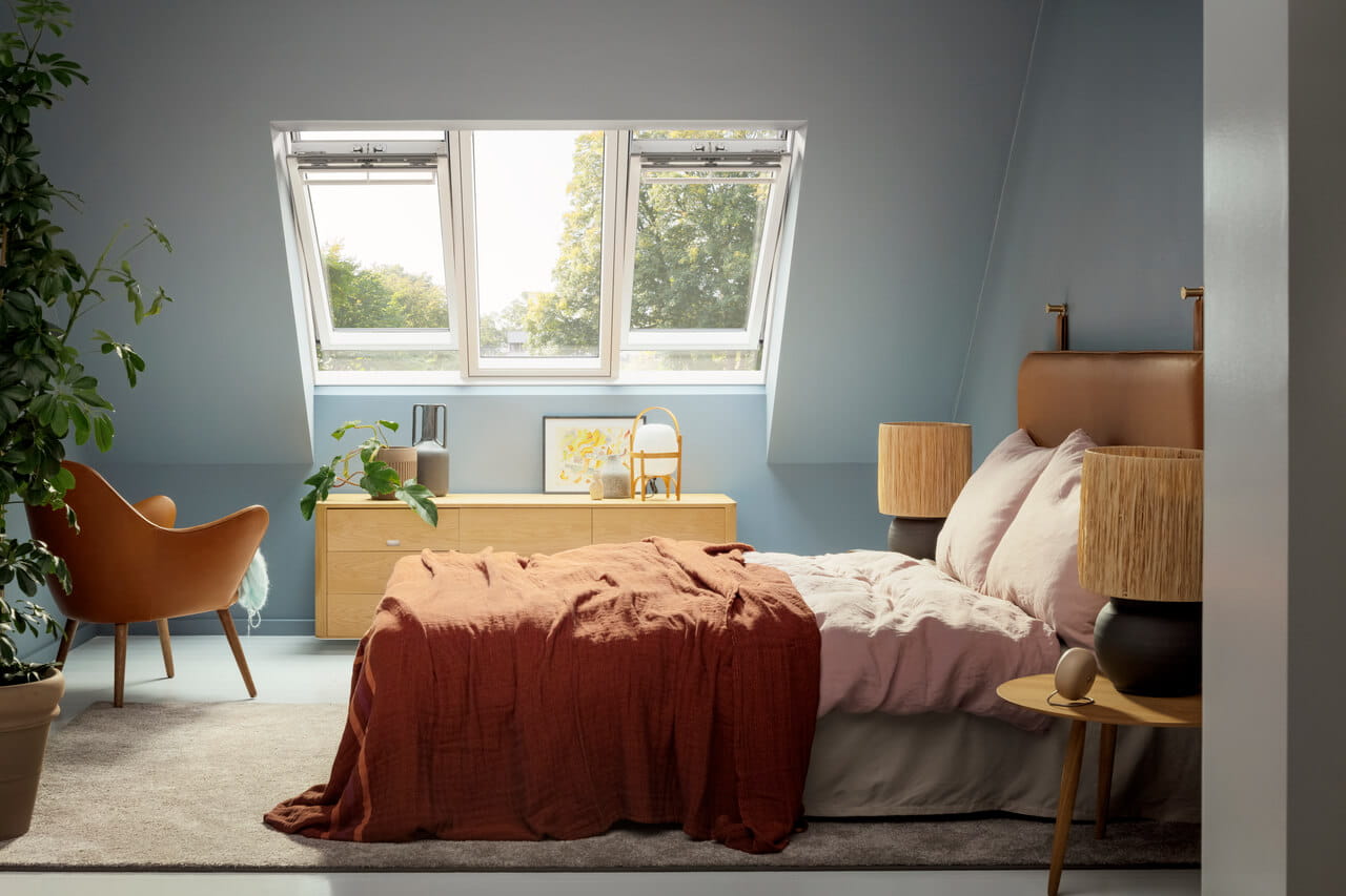 A blue painted bedroom with a bed and a chair and a 3in1 roof window