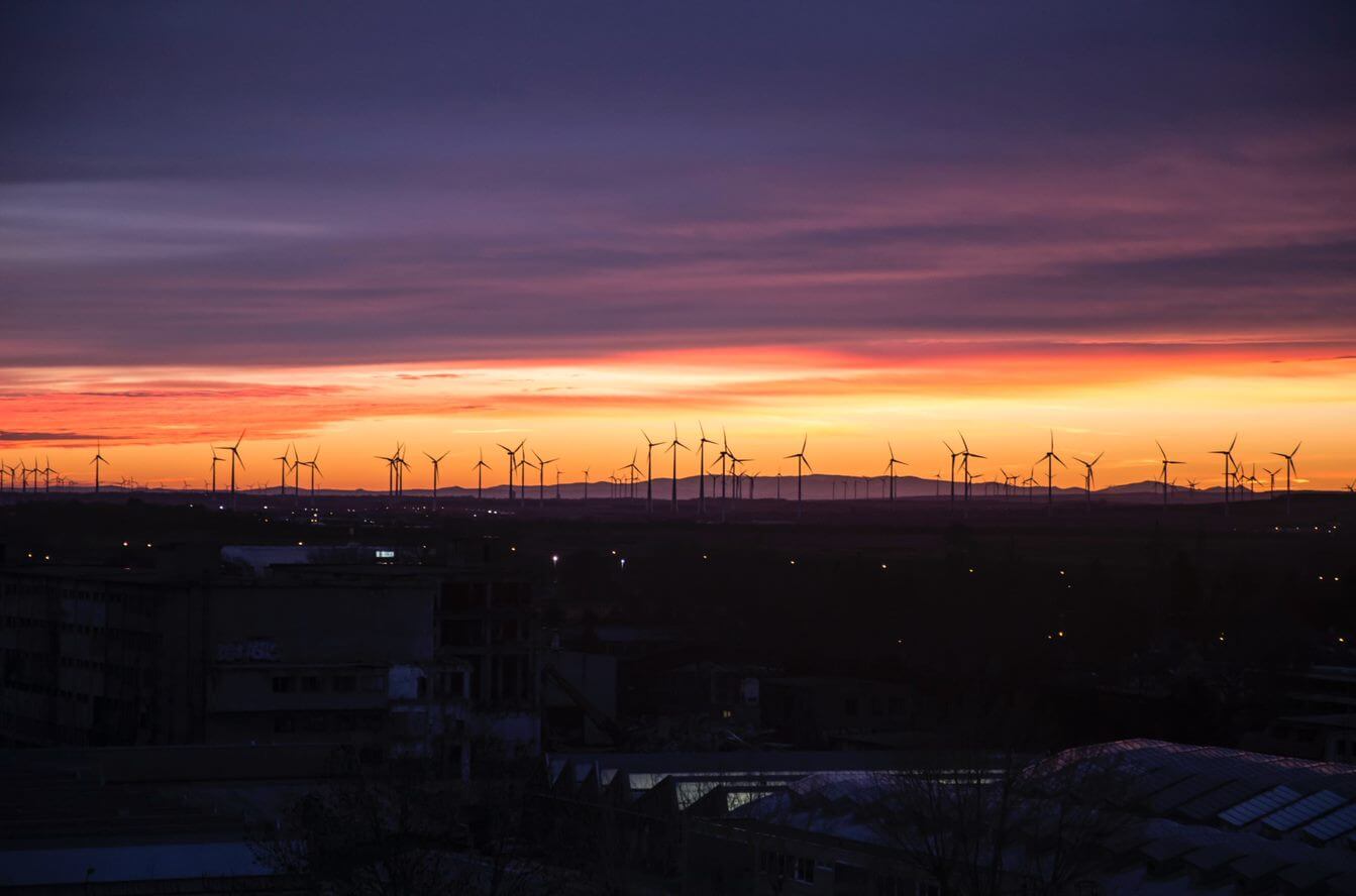 A view of sunset in the city with wind mills.