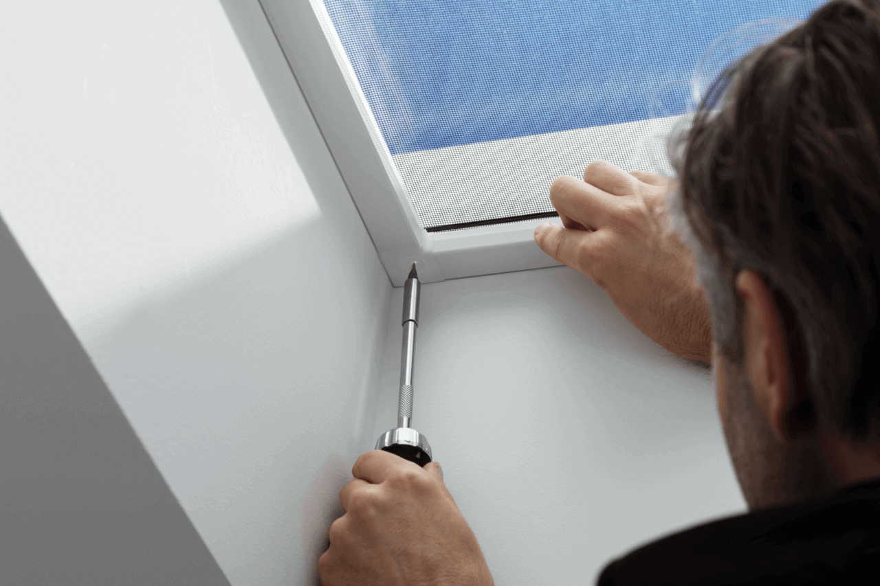 A person putting a screw in to finish roof window installation