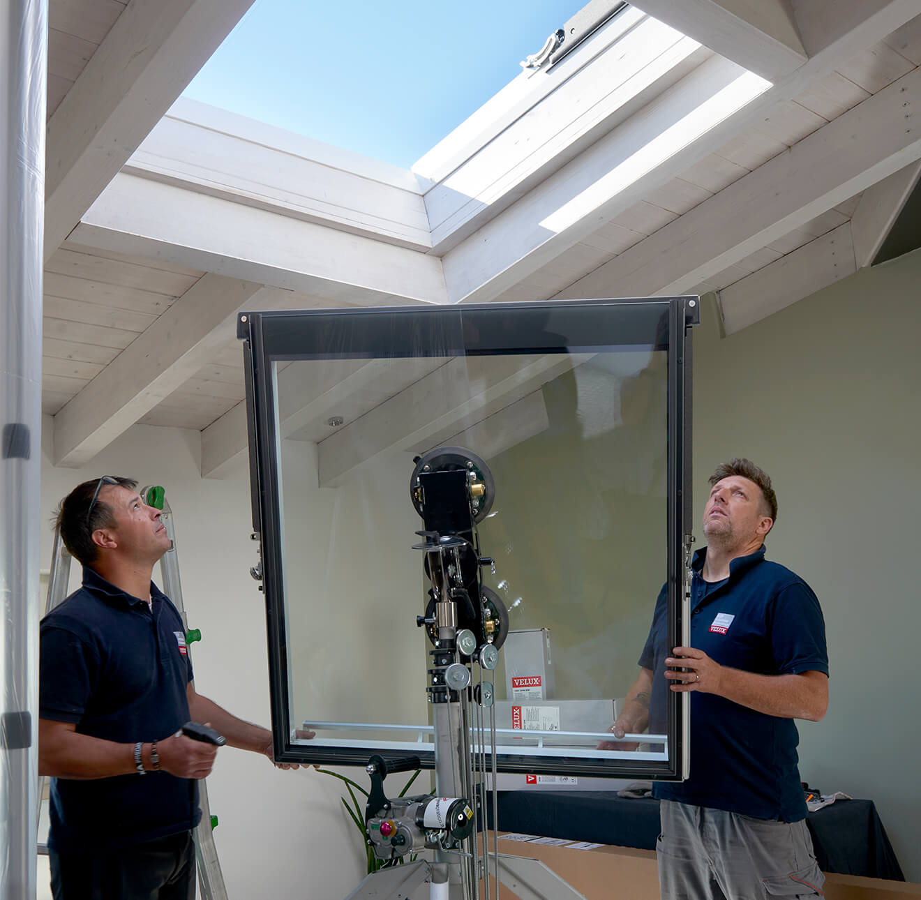 Two men holding a glass for a VELUX flat roof window.