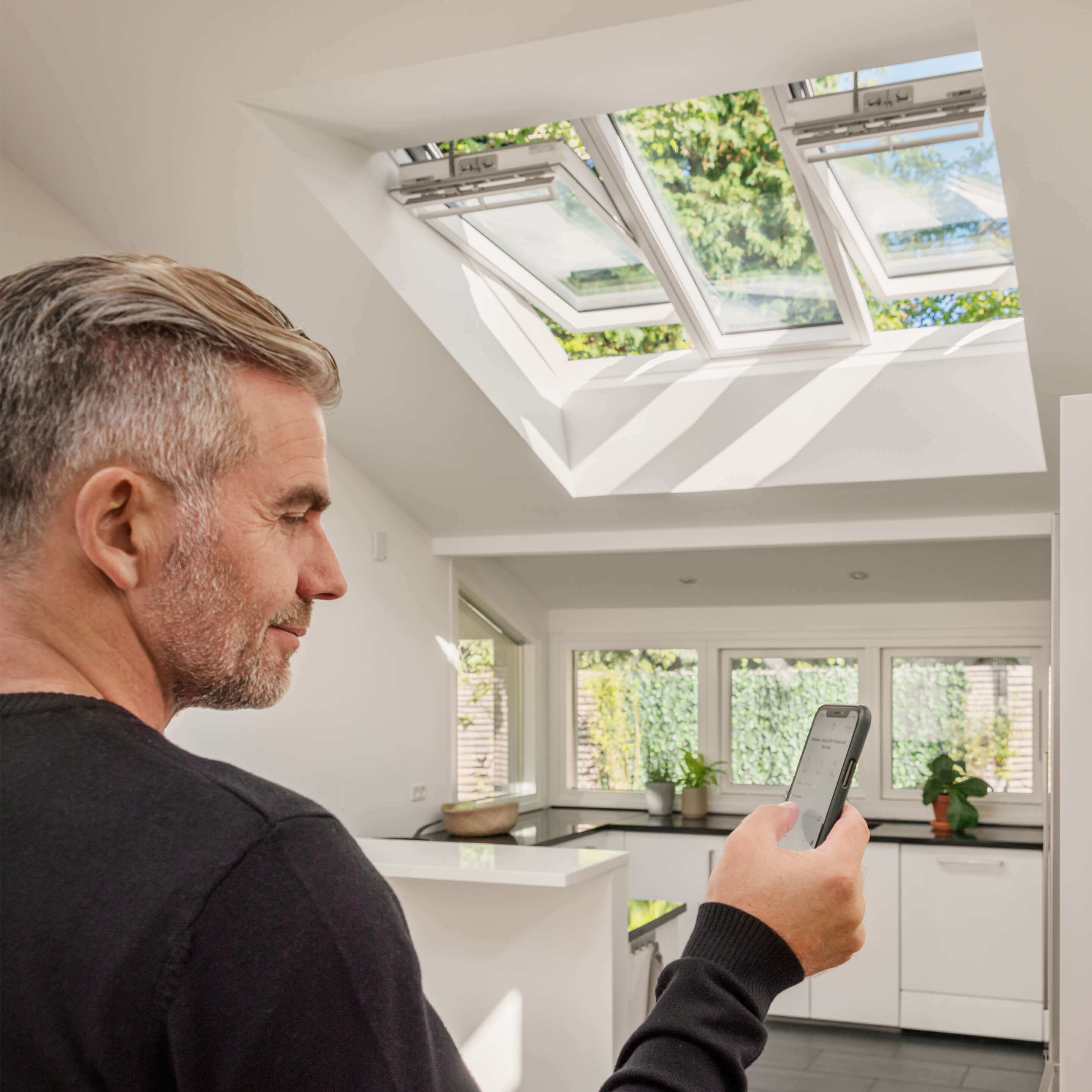 person holding a smart phone with screen showing application for controlling VELUX electric products
