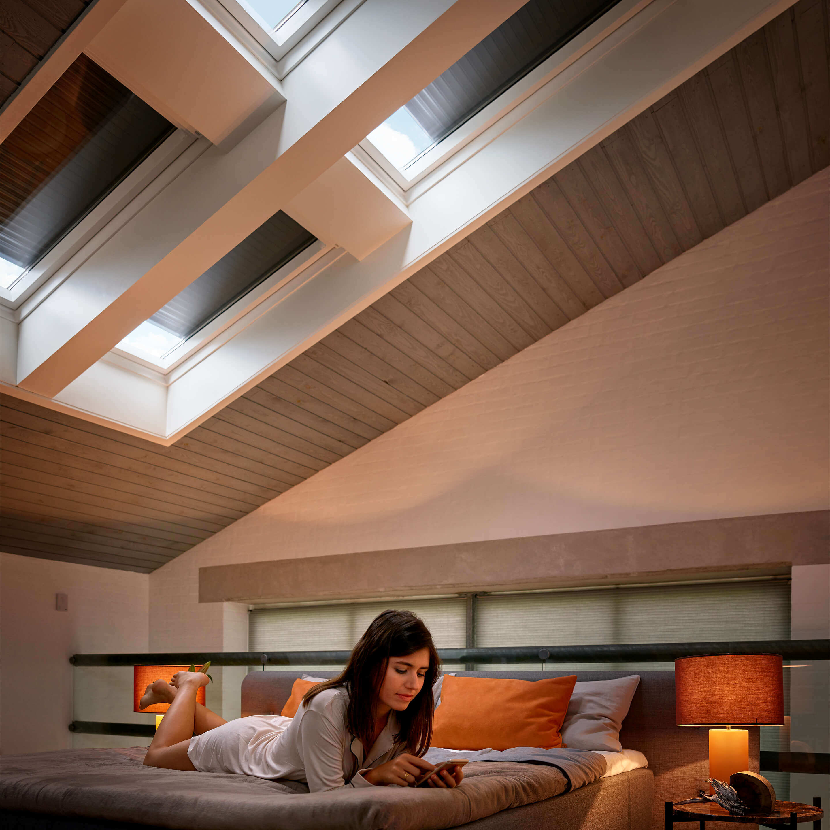 person lying on bed under four VELUX roof windows equipped with blackout blinds