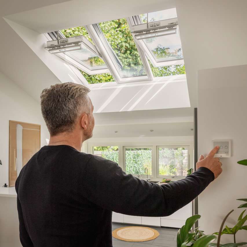 man touching VELUX Touch controller to open 3in1 roof windows in the kitchen