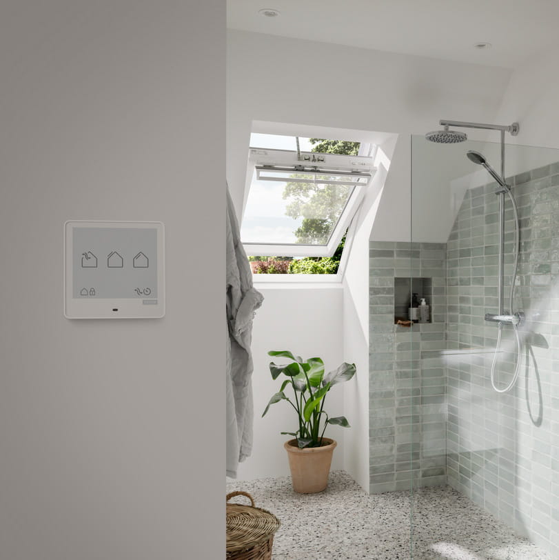Bathroom with open roof window and a VELUX Touch controller on the wall
