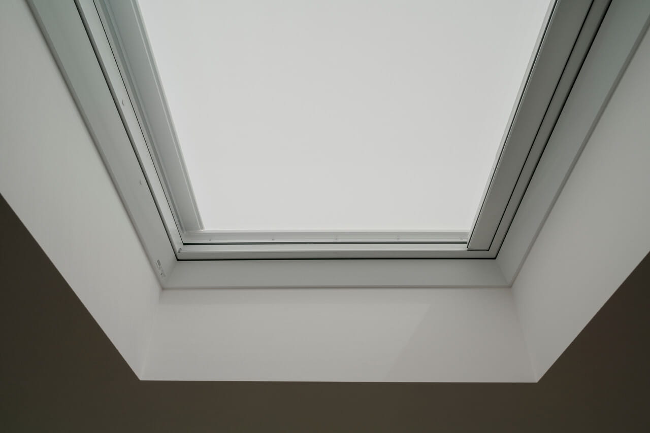 Close-up image of a VELUX flat roof window with anti-heat blinds fully rolled down.