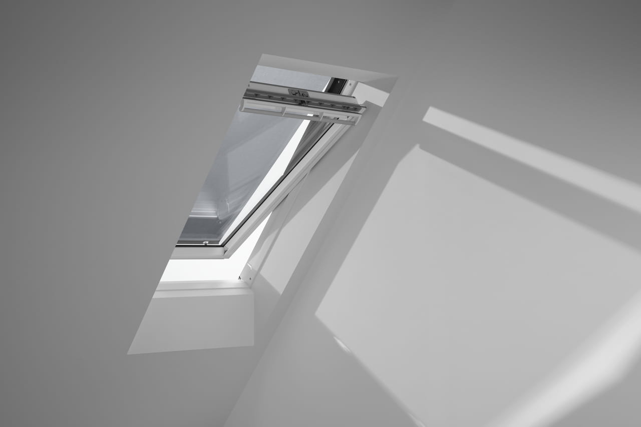 Interior image of a partially opened VELUX roof window and anti-heat blind.