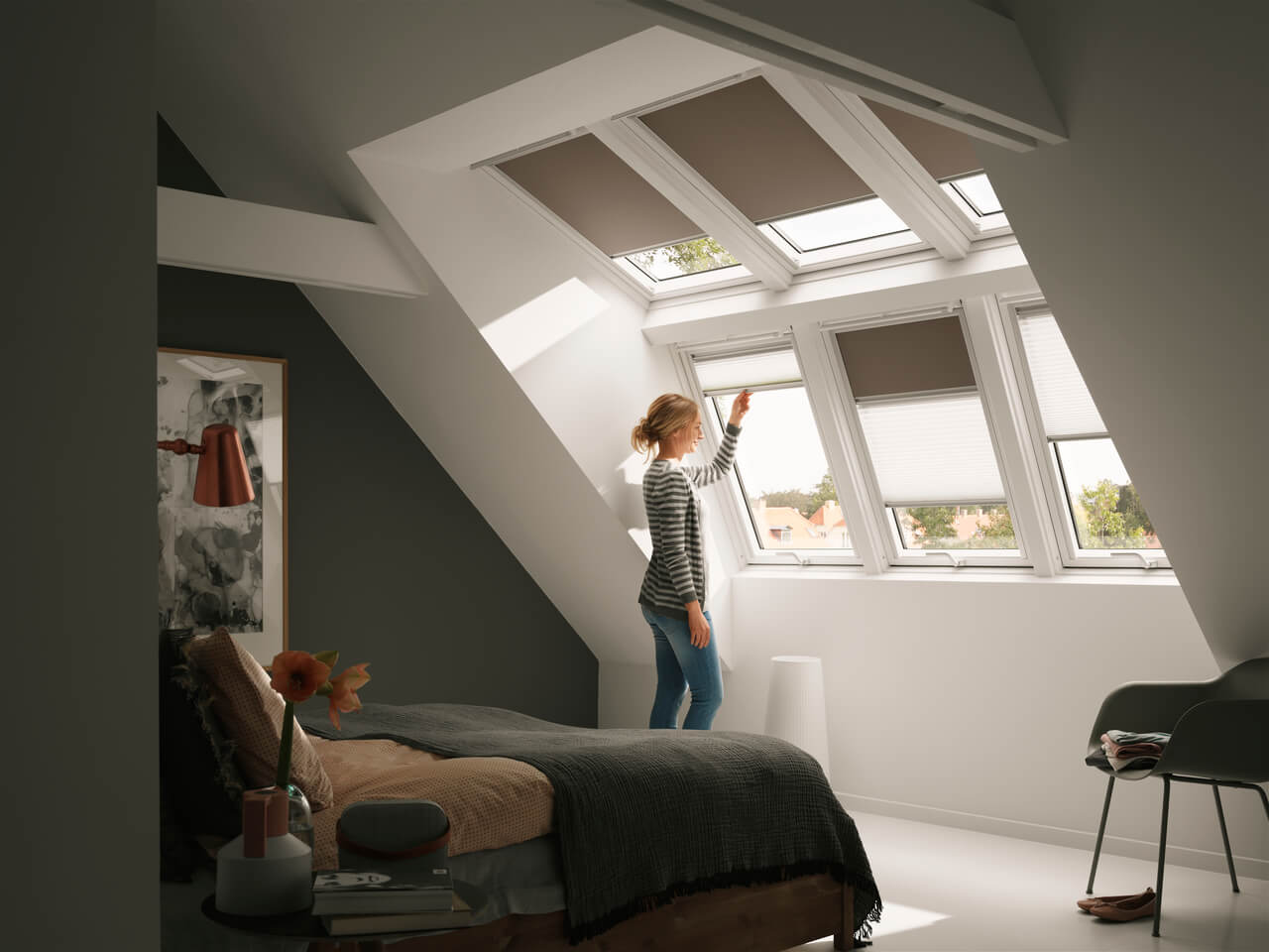 Person looking out of a bedroom and drawing a VELUX Duo blind.