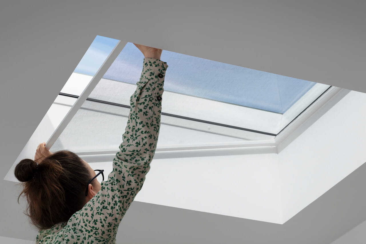 A person installing a VELUX insect screen in a flat roof window.