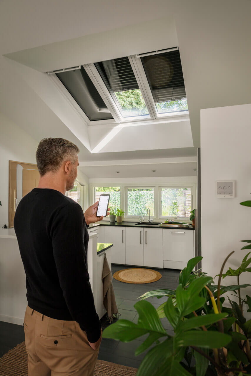 A person operating a telephone to control the VELUX roller shutters in the roof