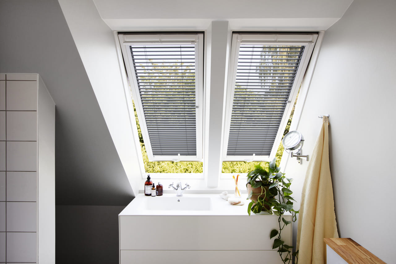 Bathroom with a yellow towel and VELUX venetian blinds installed in 2 VELUX windows