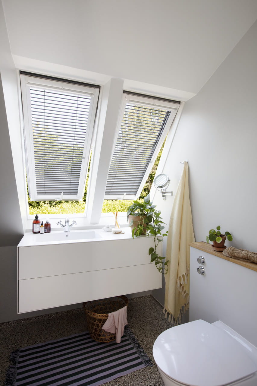 Bathroom with a yellow towel and VELUX venetian blinds installed in 2 opened windows