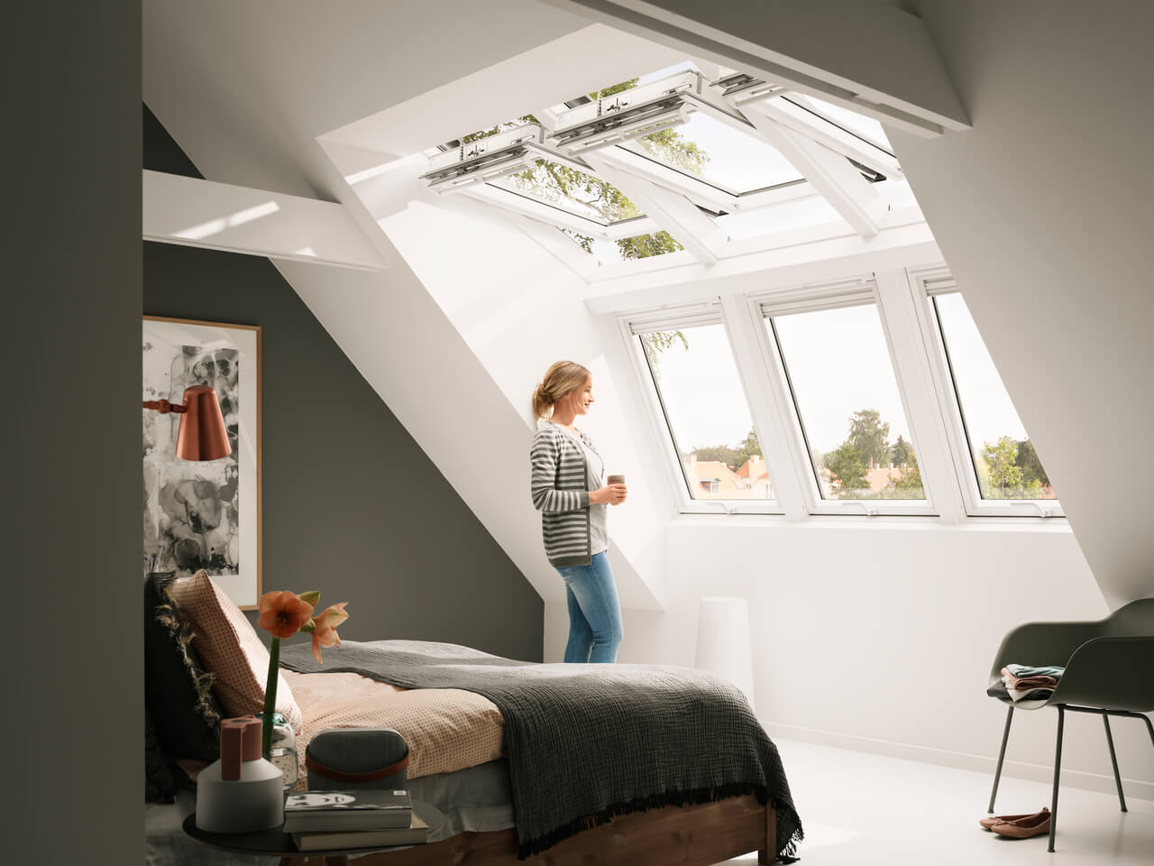 Woman standing in the bedroom and looking away from the dormer roof windows.