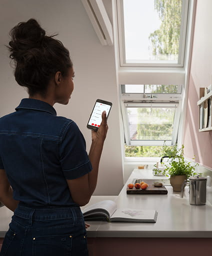 Person operating a mobile phone to control a VELUX Duo solution