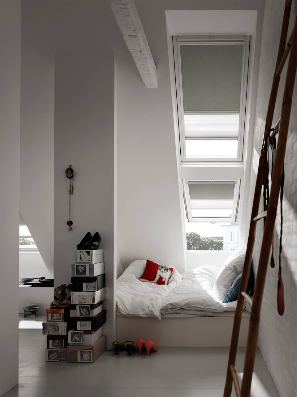 Bedroom with a ladder and greenish VELUX Duo blinds installed in the windows.