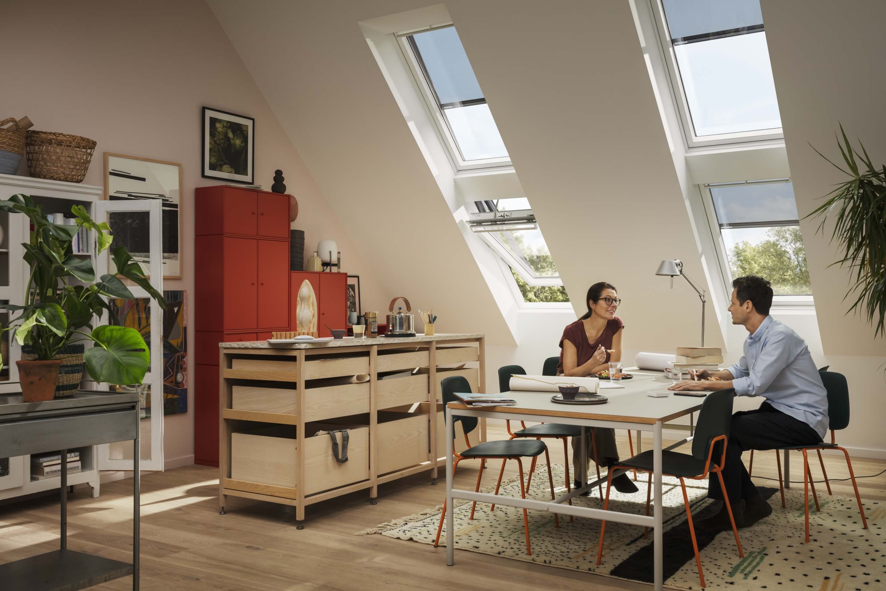 Couple sitting at a big table in a spacious room with VELUX roof windows