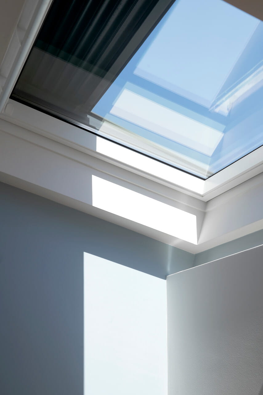 A flat roof window with half opened blind