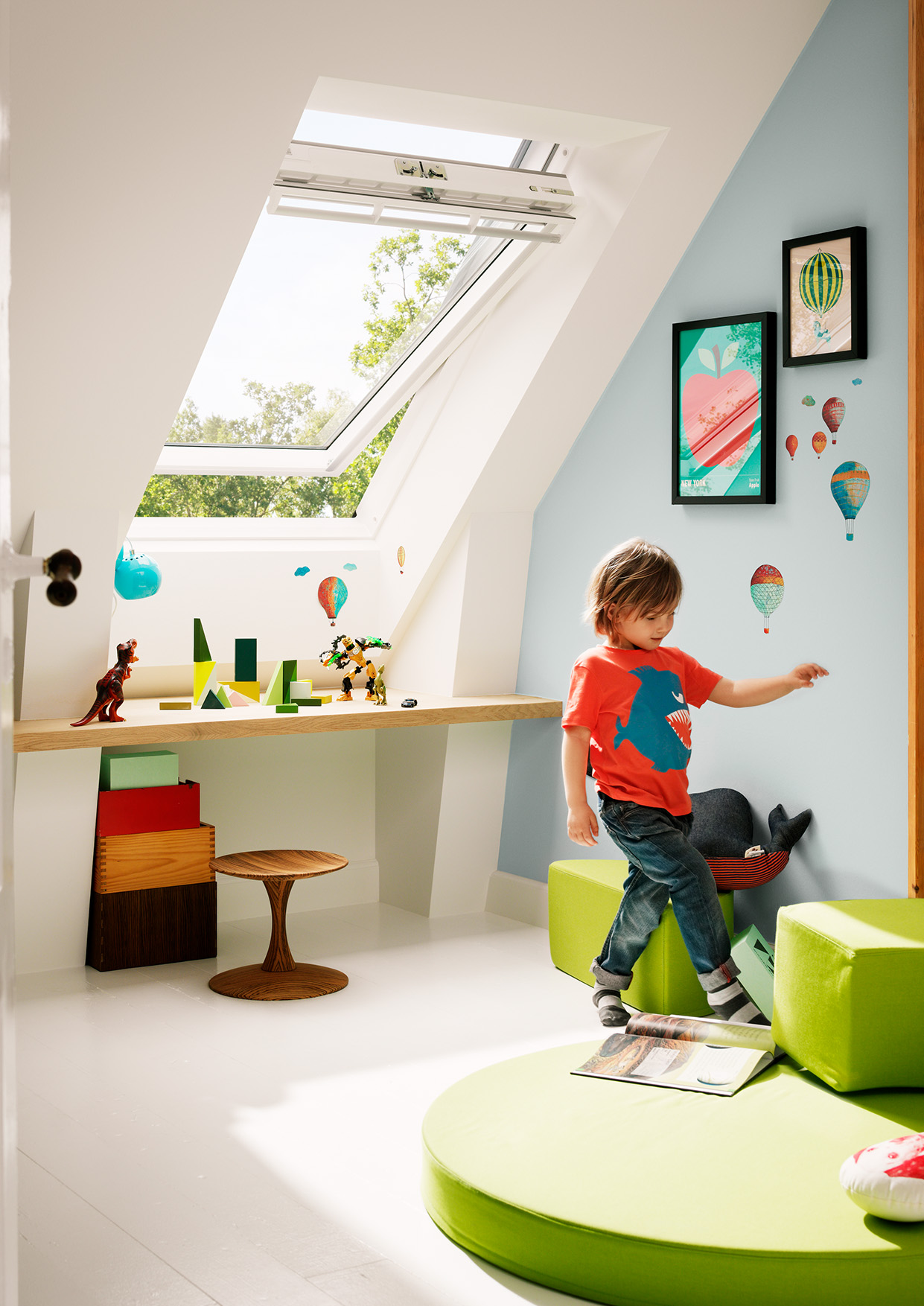 Child is playing in the bright and colourful kidsroom with roof window.