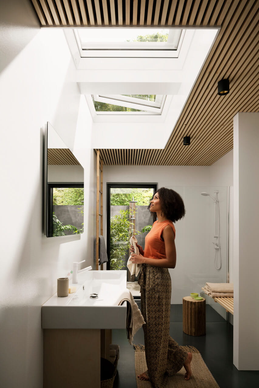 A woman in the sunny bathroom with VELUX flat roof windows