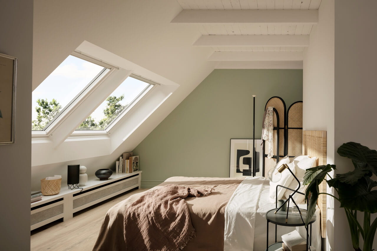 A sunny bedroom with a bed in front of roof windows