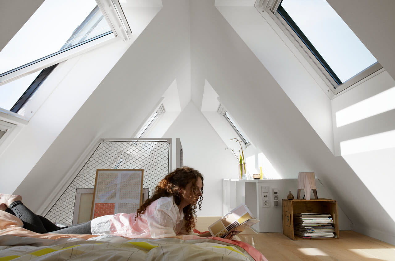 Bedroom in the attic with a woman lying on the bed and reading