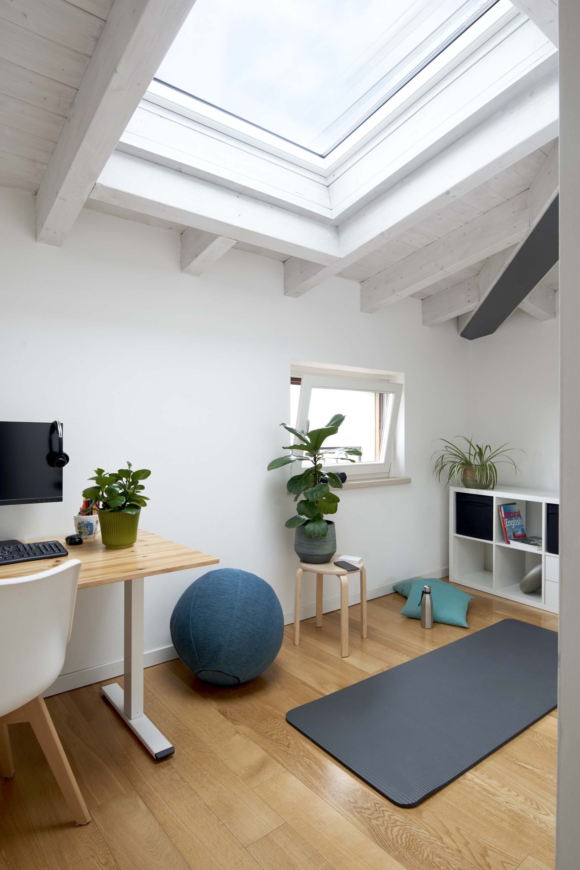 Home office area with some sports equipment on the floor and flat roof window that gives a lot of light in the room