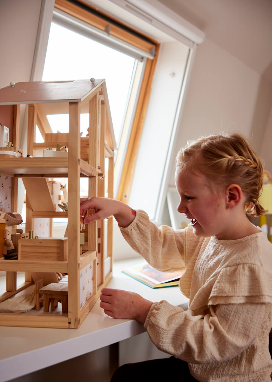 Girl playing with the wooden doll house.