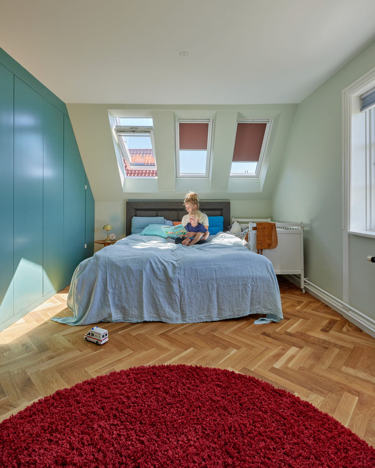 Bright and colourful bedroom with a person sitting on the bed.
