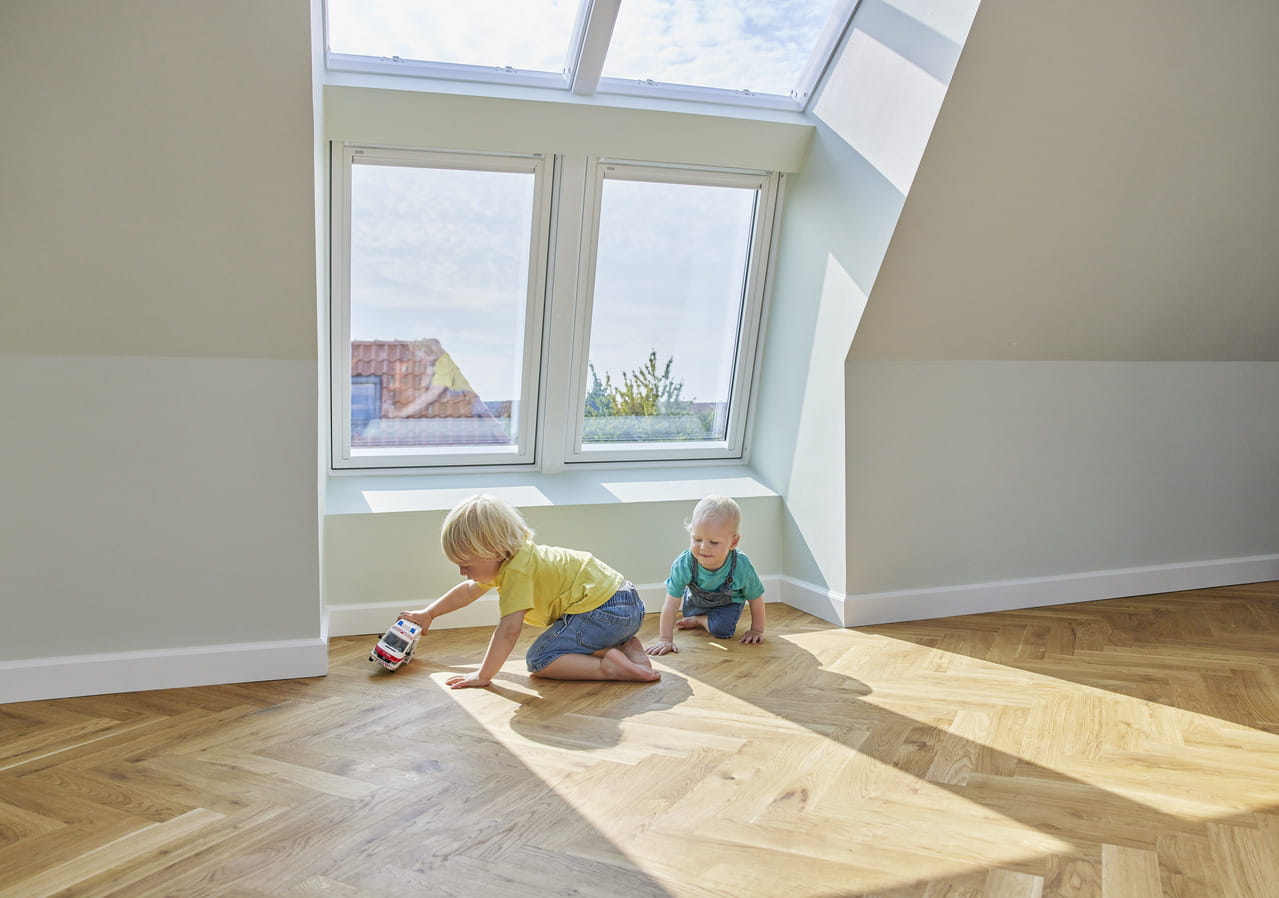 Two kids playing on the floor by the roof windows.