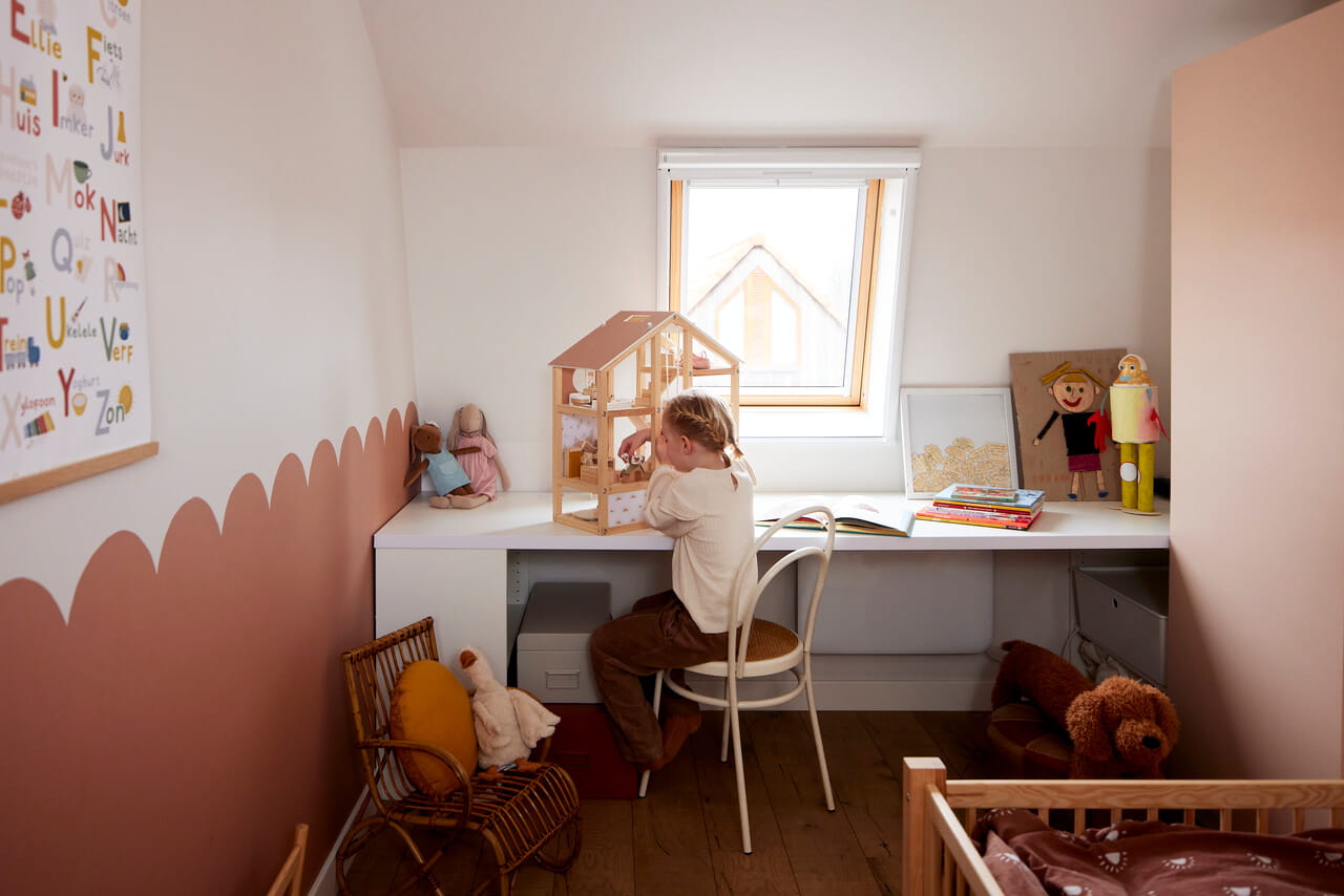 A girl playing in her room with a doll house.