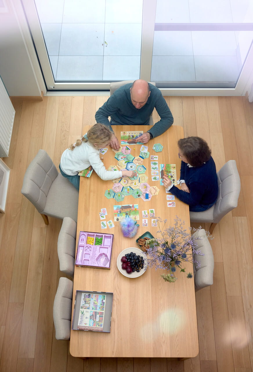 A view from the top to a family playing board game by the dining room table.