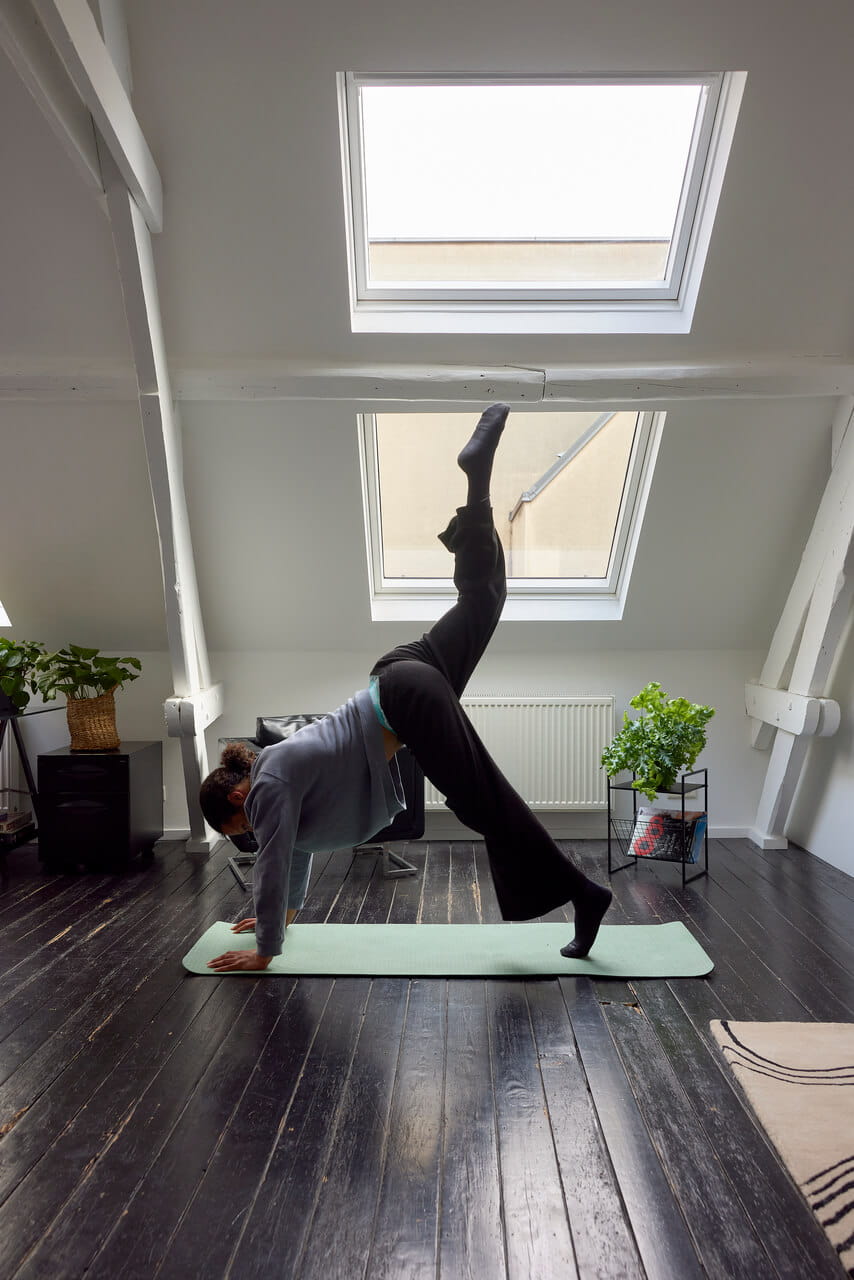 Woman doing yoga in front of roof window.