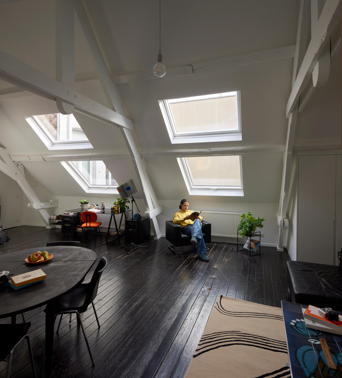 An attic area with a person sitting by the roof window.